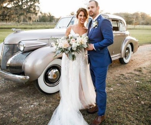 Newlyweds beside a vintage wedding car after their ceremony